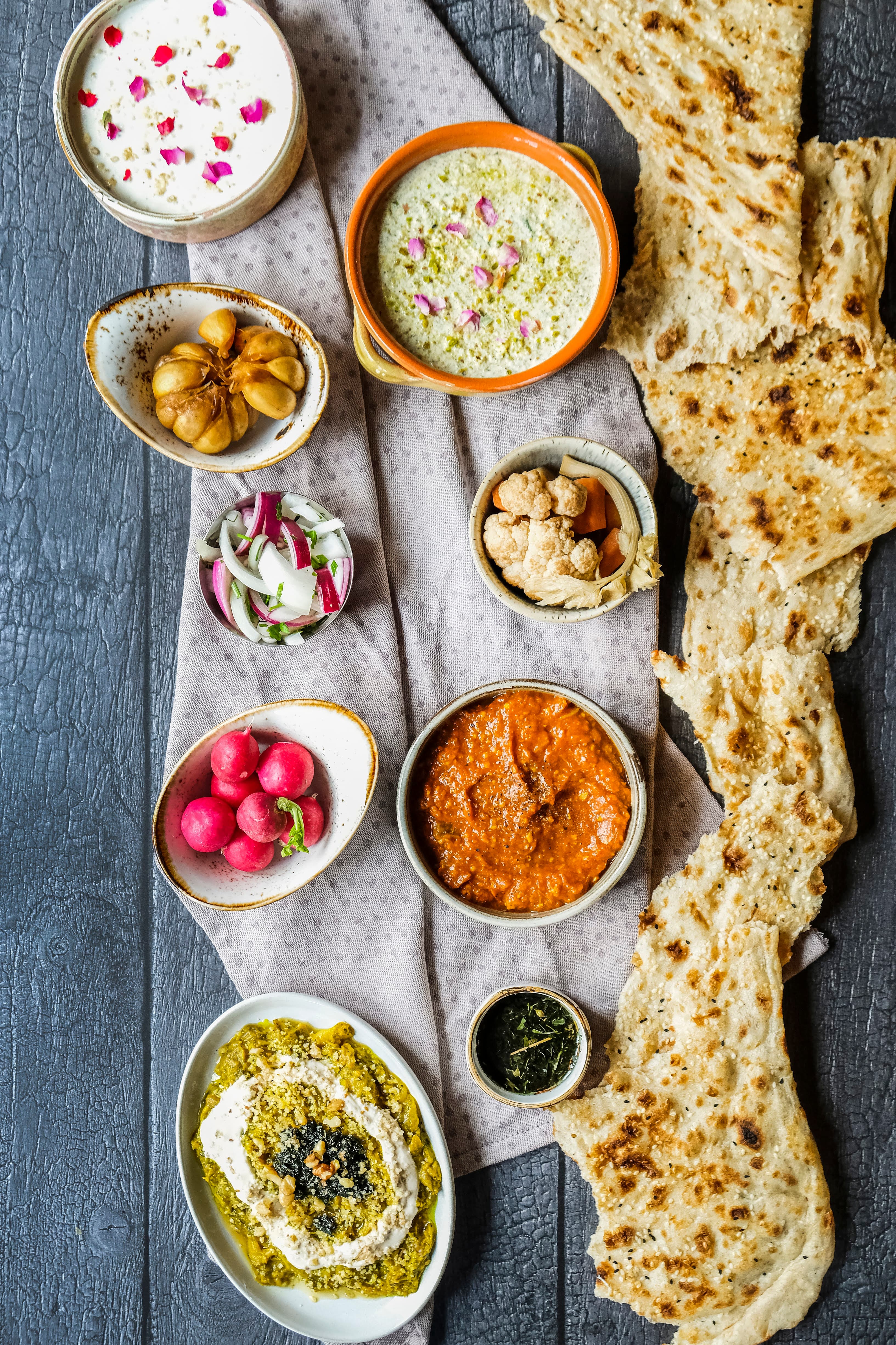 A sharing board laid out on cloth — dips, pickles, radishes and sangak flatbread